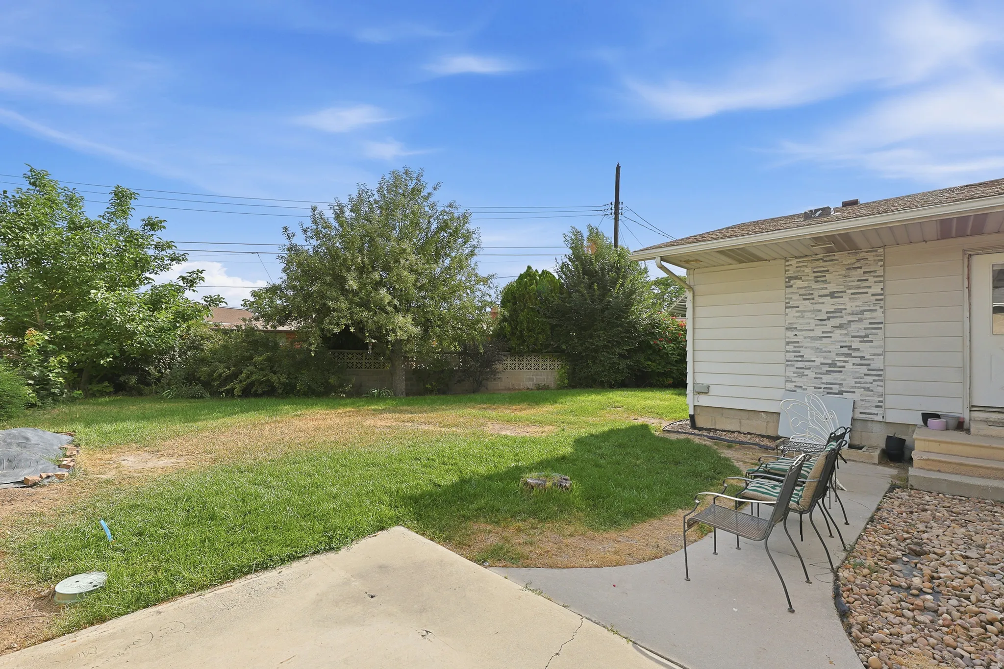 Spacious backyard featuring a concrete patio, mature trees, and a privacy fence