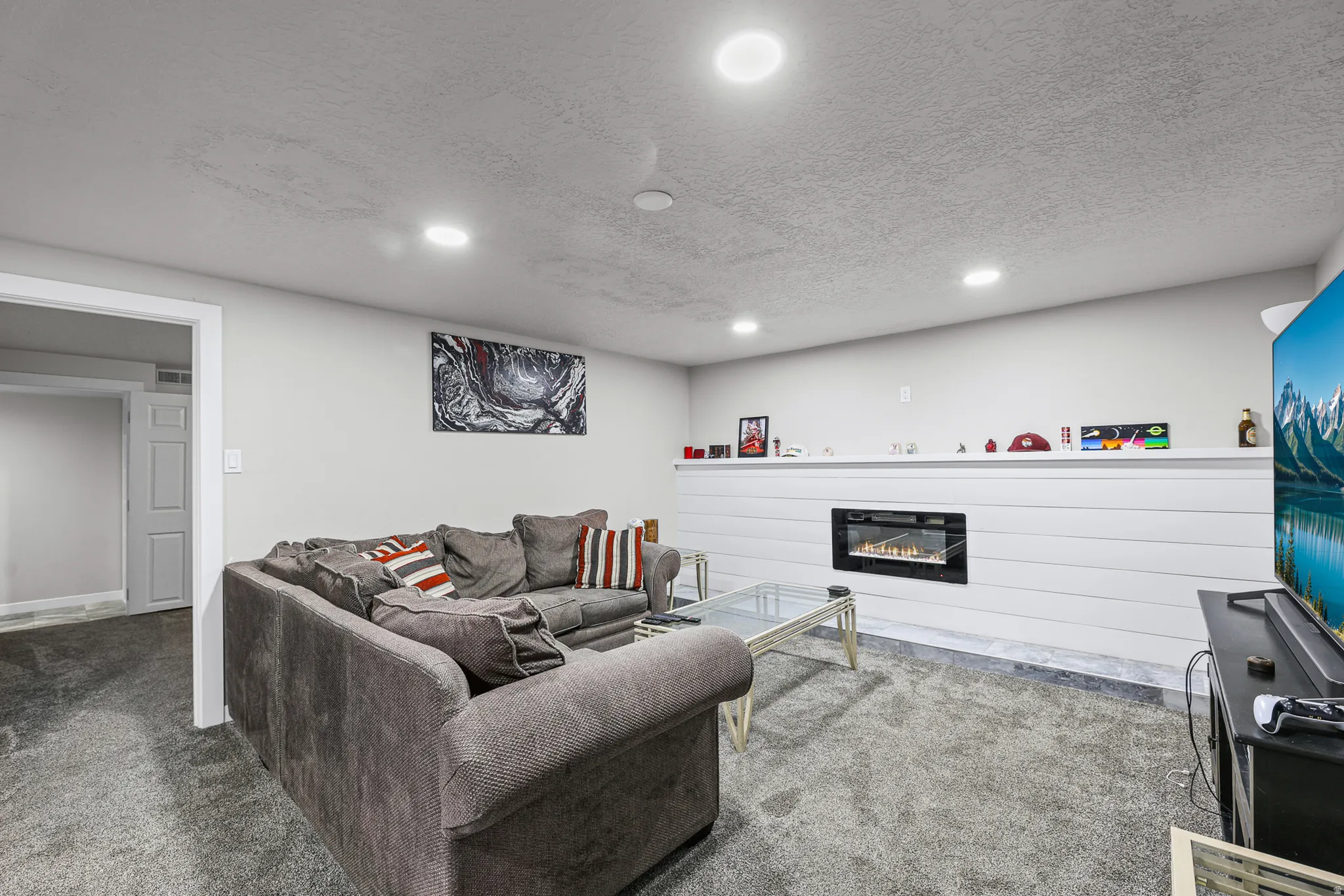 Recessed lighting illuminates this living space featuring a shiplap accent wall with a built-in electric fireplace
