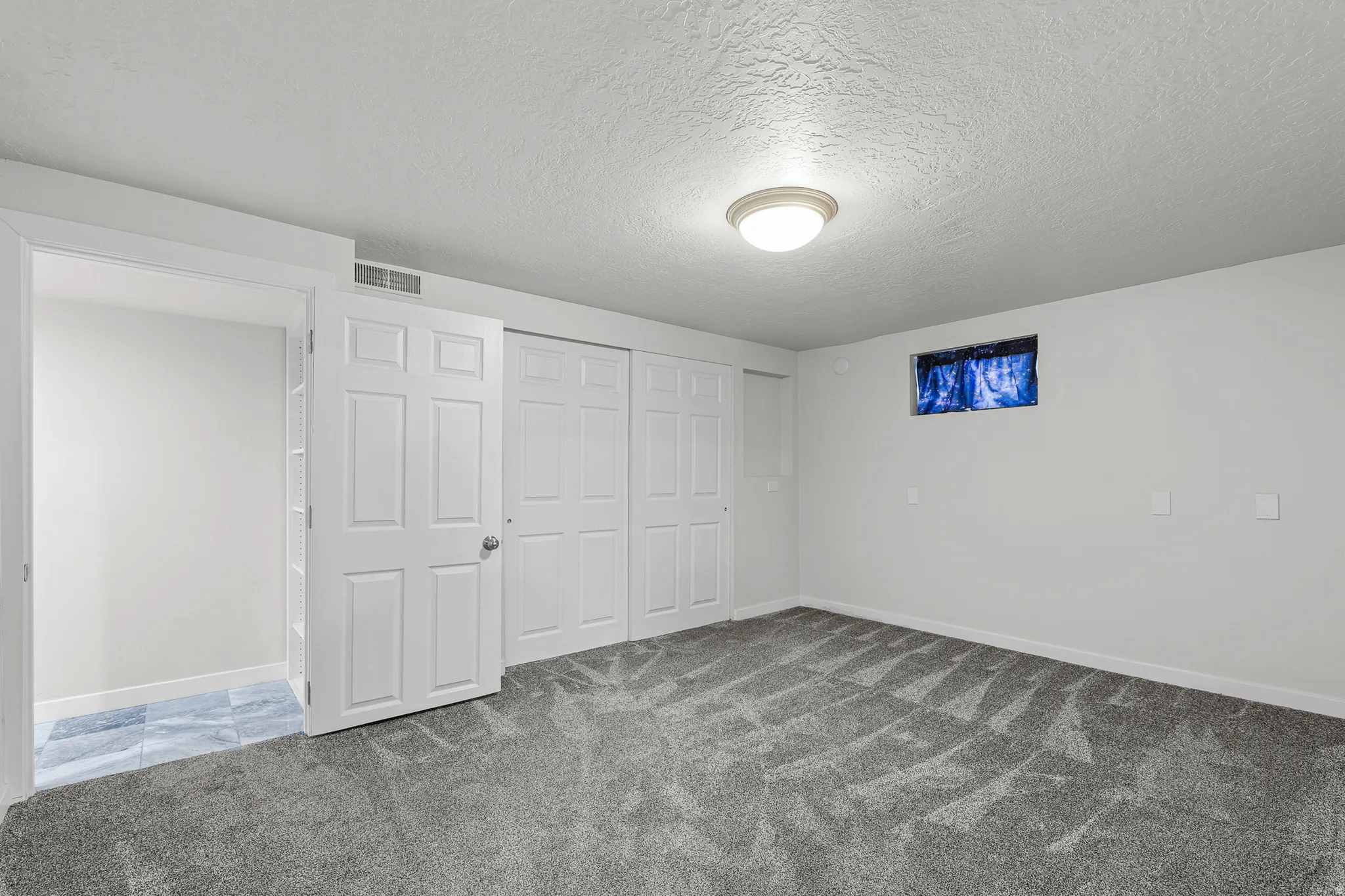 Spacious room featuring gray patterned carpet flooring