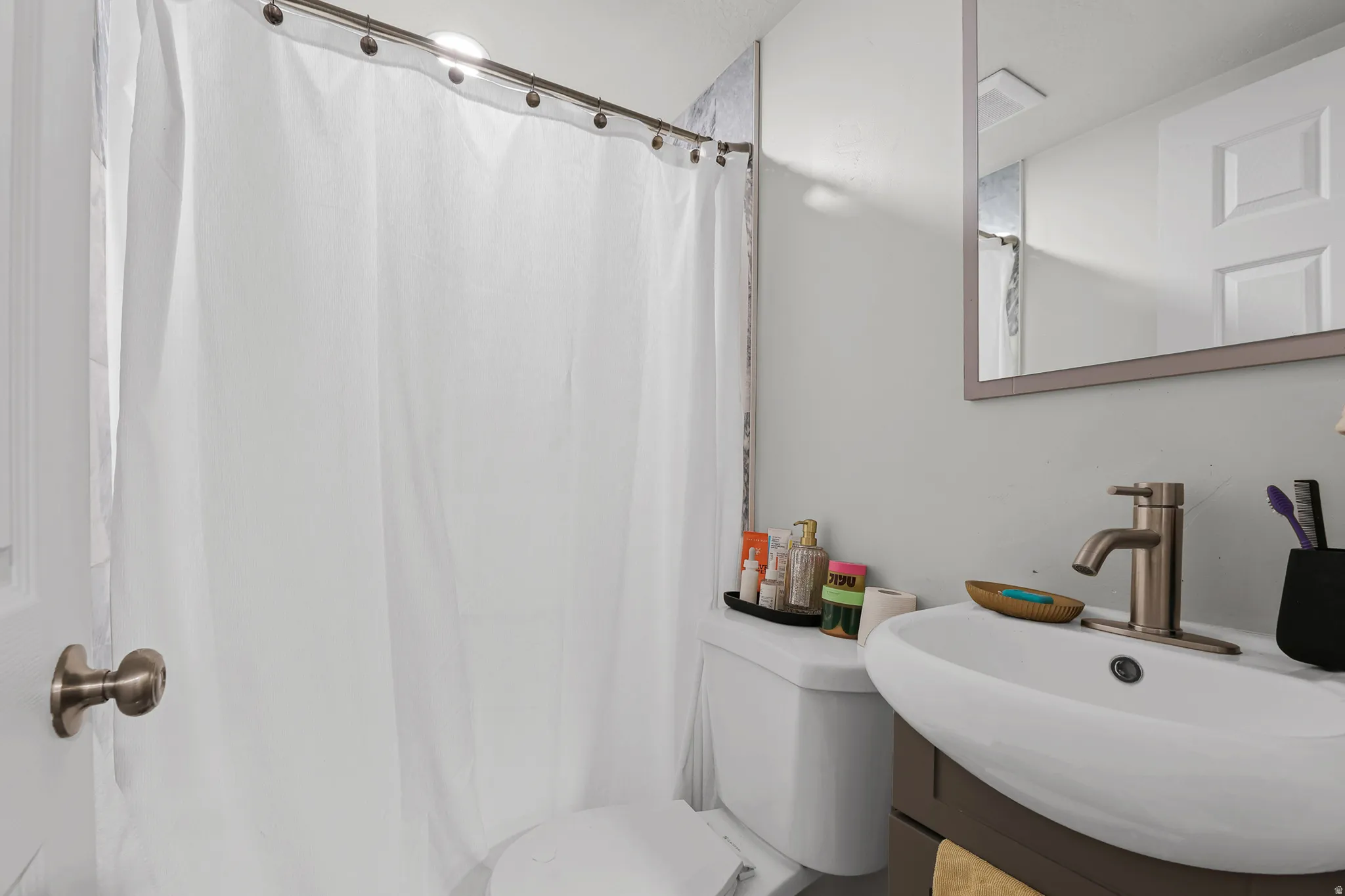 Bathroom featuring a modern vanity with a vessel sink, a brushed nickel faucet, an overhead mirror, and a white toilet