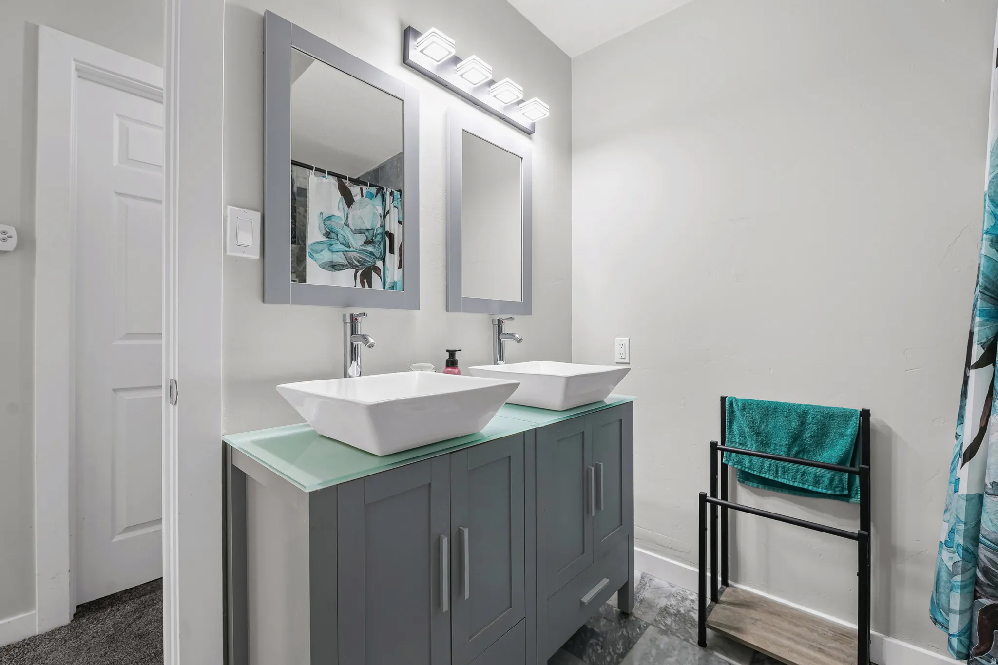 Dual vessel sinks with chrome faucets set on a contemporary vanity with a frosted glass countertop