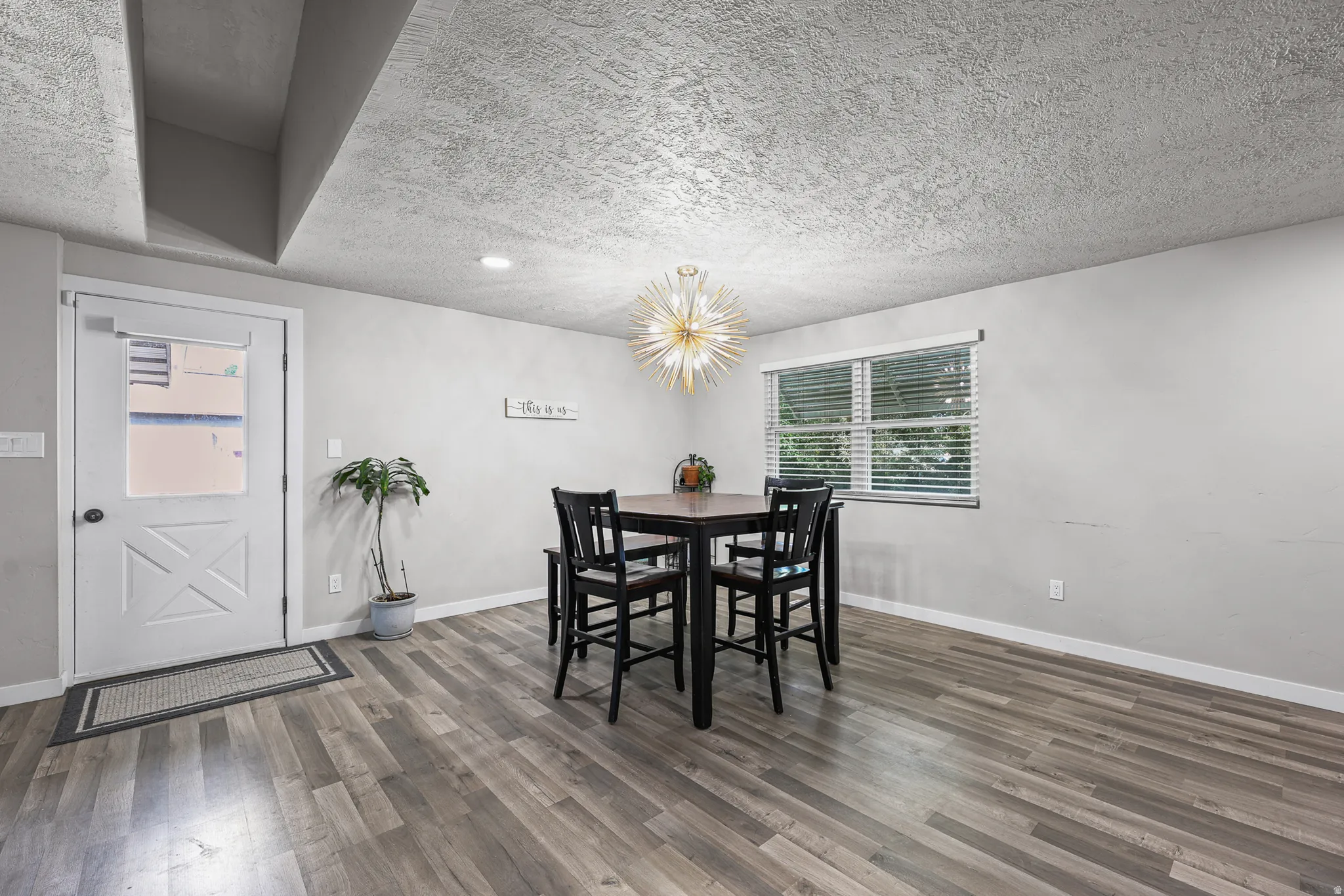 Dining area featuring wood-finish flooring, a modern sputnik chandelier, and a large window with blinds