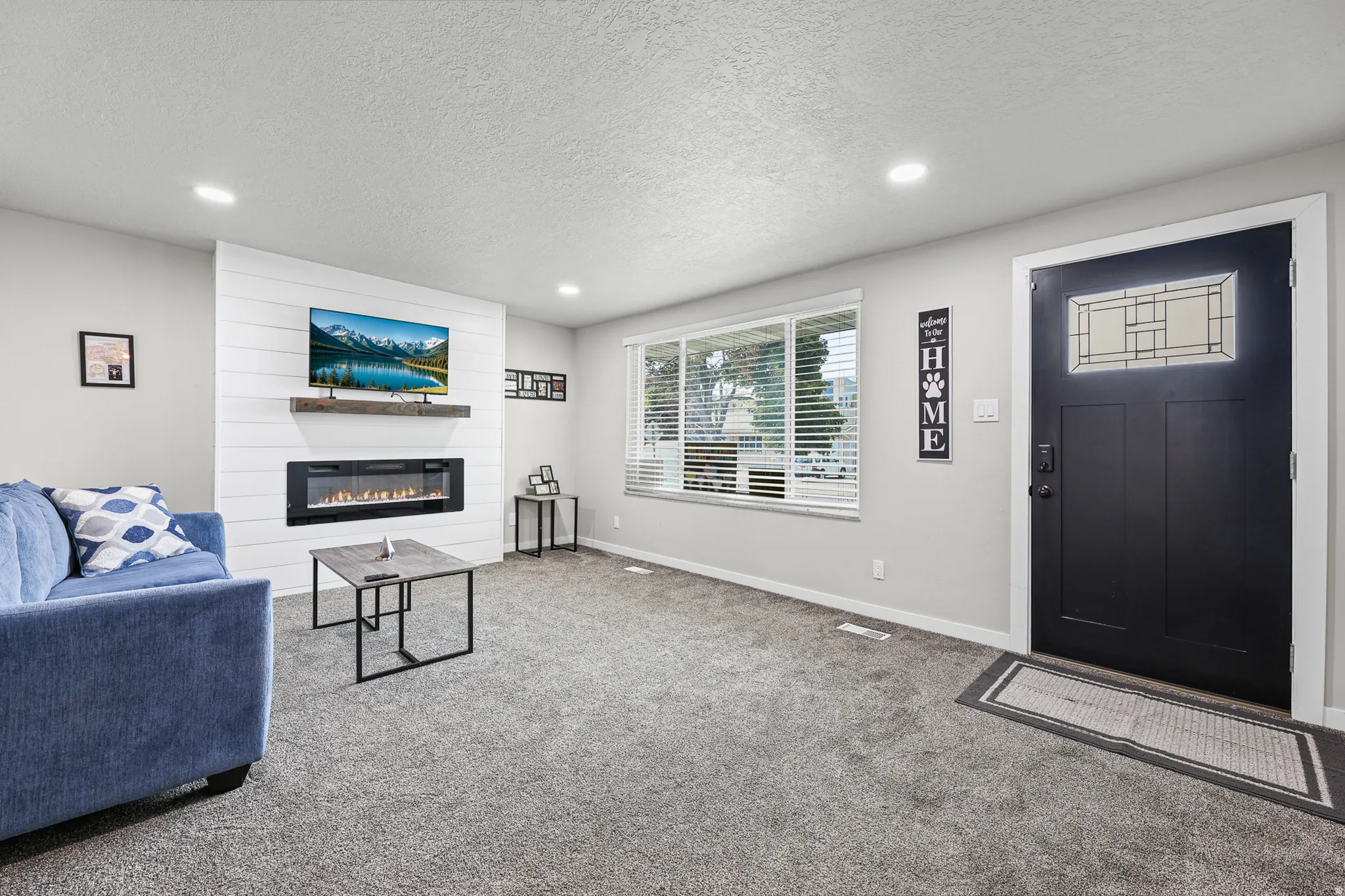 Living area featuring an electric fireplace with a wood mantle and shiplap accent wall