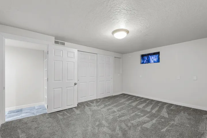 Spacious room featuring gray patterned carpet flooring