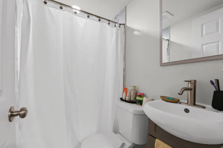 Bathroom featuring a modern vanity with a vessel sink, a brushed nickel faucet, an overhead mirror, and a white toilet
