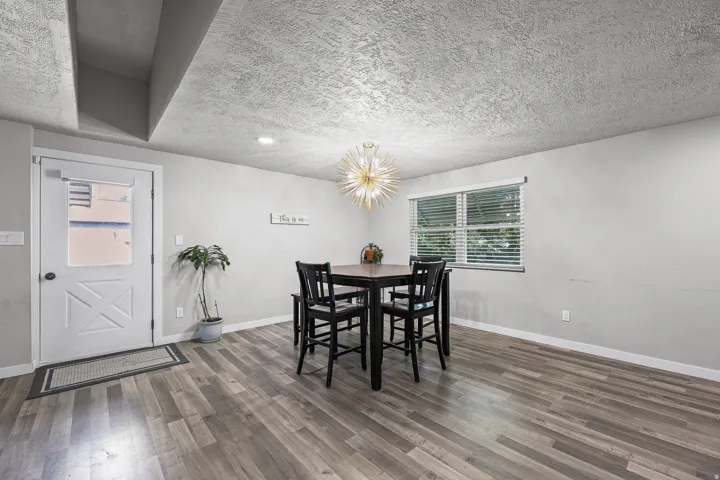 Dining area featuring wood-finish flooring, a modern sputnik chandelier, and a large window with blinds
