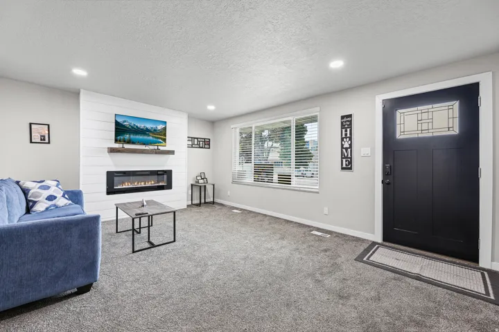 Living area featuring an electric fireplace with a wood mantle and shiplap accent wall