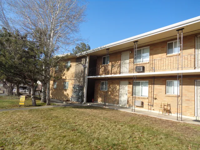 Brick exterior featuring multiple private balconies, ground-level patios, and mature landscaping
