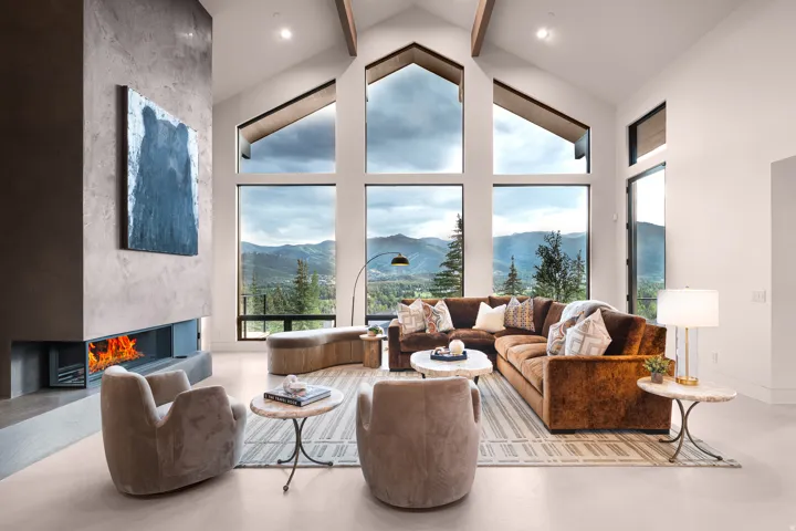 Vaulted ceilings with exposed beams, full-height windows, a built-in fireplace, and light-tone flooring