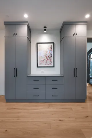 Built-in cabinetry in a neutral gray finish with black hardware, featuring a combination of full-height storage and six drawers