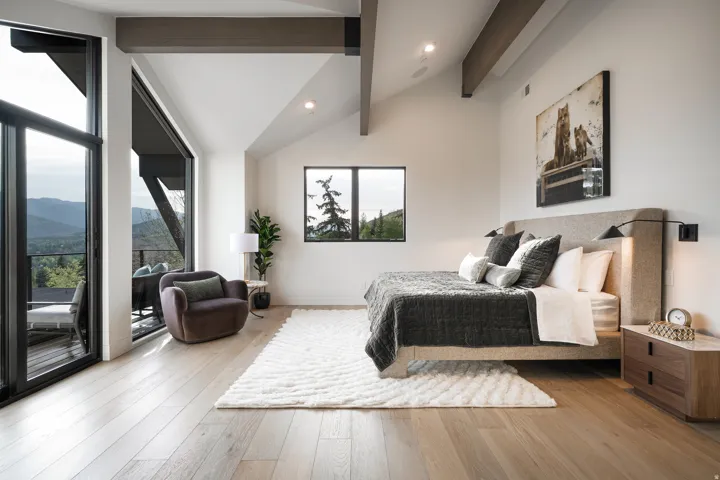 Vaulted ceilings with exposed beams, light wood-finish flooring, recessed lighting, expansive glass sliding doors, and a large picture window