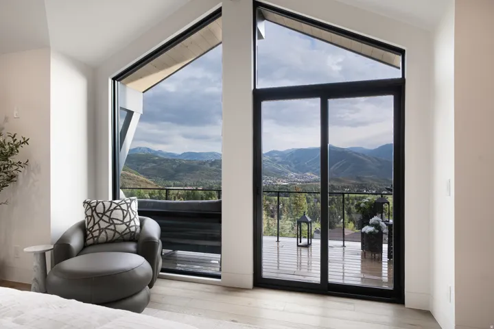 Sliding glass doors opening to an outdoor deck, complemented by an angled transom window, light wood-finish flooring, and white painted walls