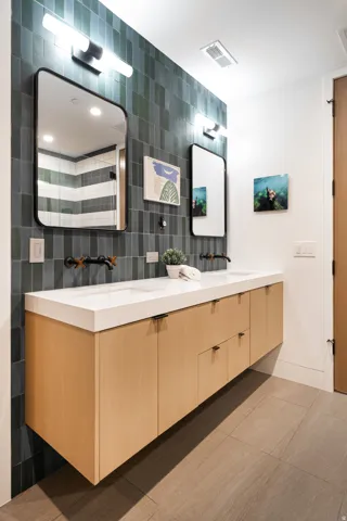Floating wood-finish double vanity with integrated sinks, black fixtures, and a tiled accent wall