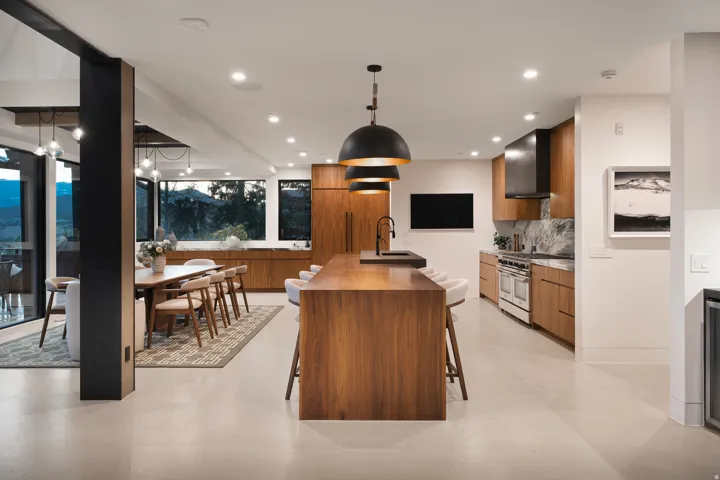 Open-concept kitchen and dining area featuring wood-finish cabinetry, a large kitchen island with seating, a professional-grade range, and a full-height marble backsplash