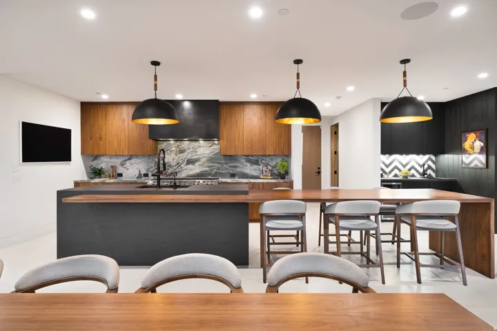 Central kitchen island with a dark finish, wood-tone cabinetry, and a marbled backsplash