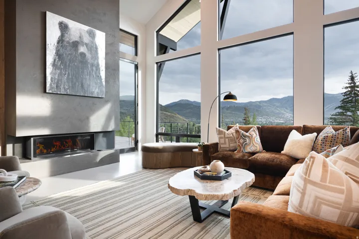 Floor-to-ceiling windows, soaring ceilings, an integrated linear fireplace, and a concrete-finish hearth and wall