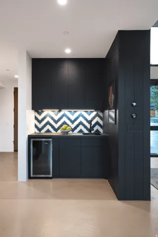 Built-in wet bar featuring dark cabinetry, an integrated beverage cooler, and a patterned tile backsplash