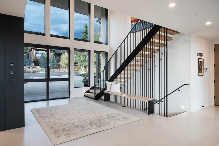 Two-story entry featuring expansive windows, a floating staircase with metal railings, and light-colored flooring