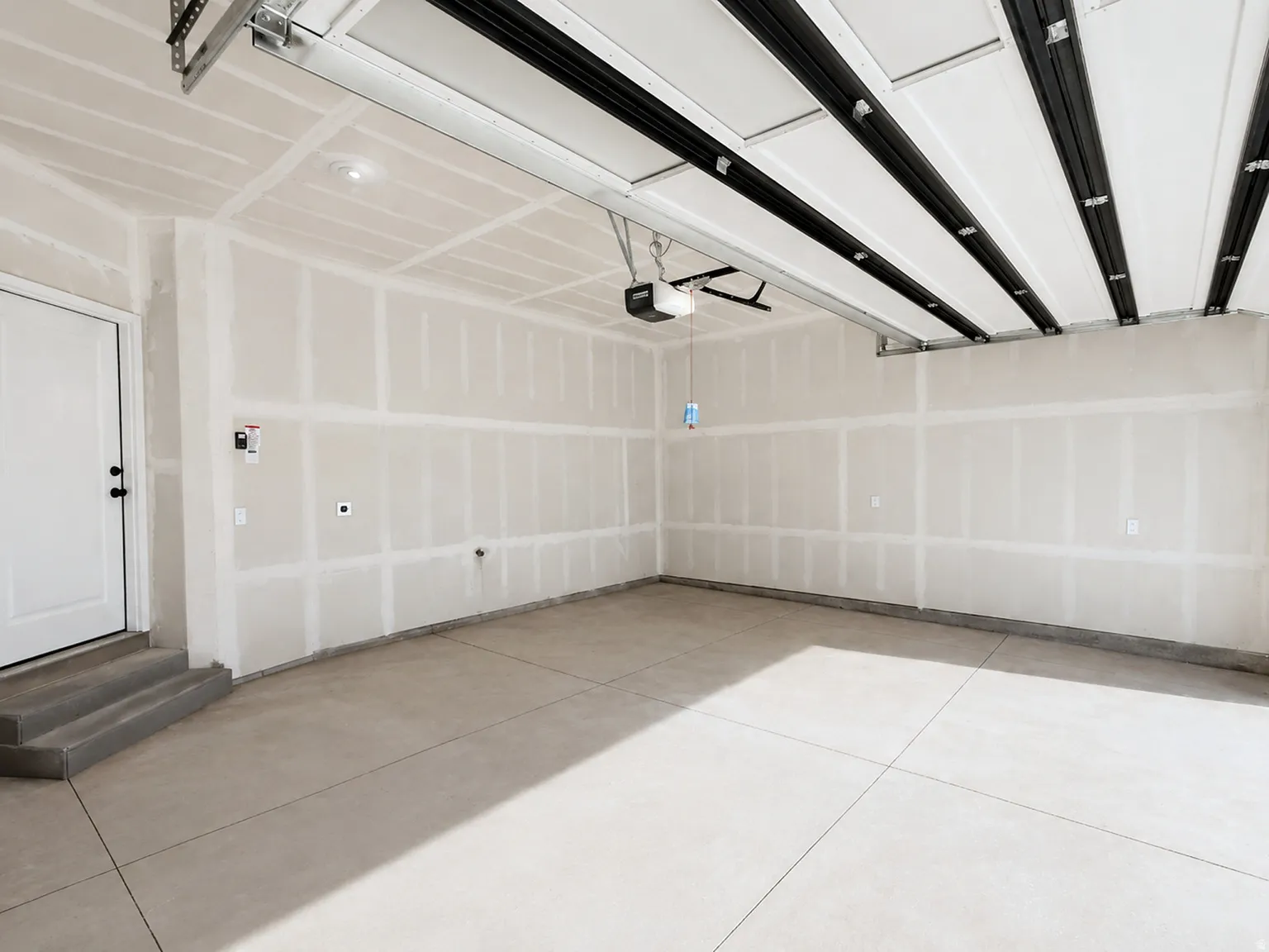 Spacious garage featuring concrete flooring and a white entry door