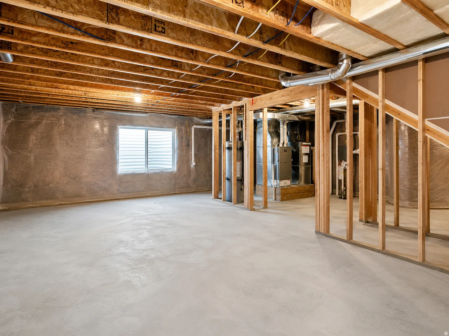 Unfinished basement featuring exposed wood framing, concrete flooring, and a horizontal sliding window