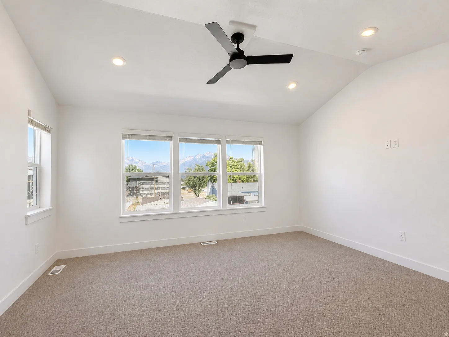 Spacious room featuring vaulted ceilings, a contemporary ceiling fan, recessed lighting, and expansive windows offering mountain scenery