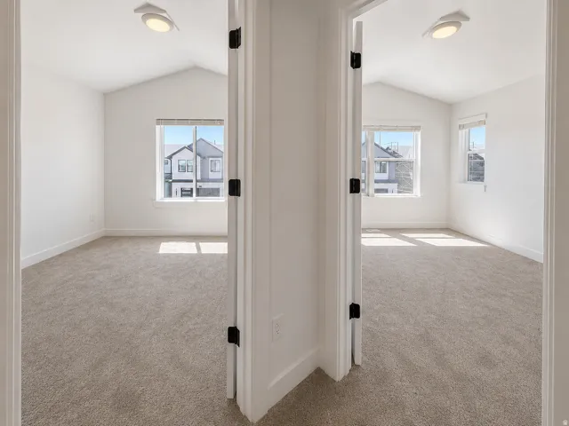 Two rooms featuring vaulted ceilings, carpet flooring, and white trim