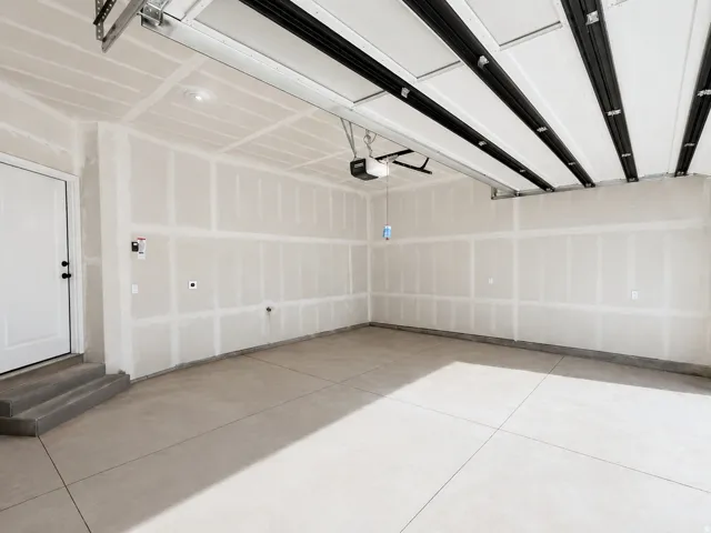 Spacious garage featuring concrete flooring and a white entry door
