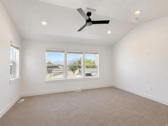 Spacious room featuring vaulted ceilings, a contemporary ceiling fan, recessed lighting, and expansive windows offering mountain scenery