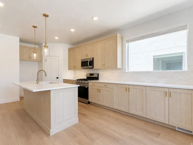 Modern kitchen featuring light wood-finish cabinetry and gold-tone hardware