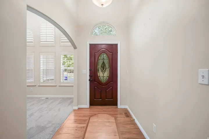 Wood-finish flooring entry with a decorative oval glass front door and arched transom window
