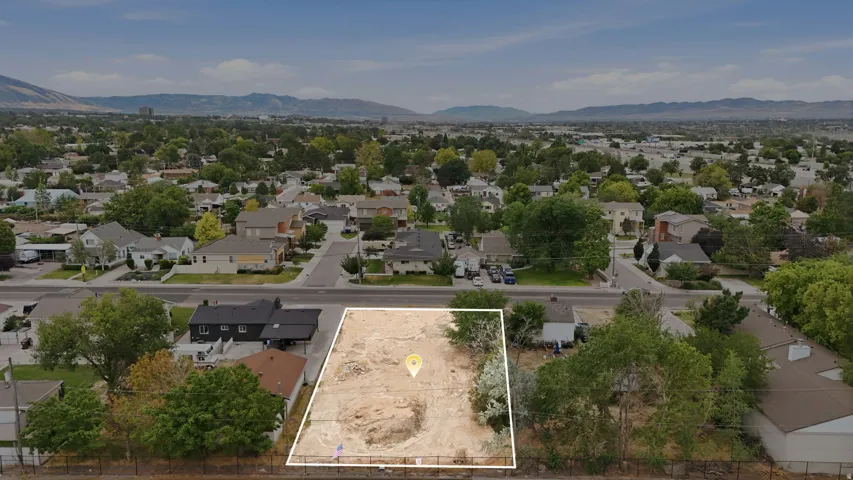 Expansive vacant lot featuring a cleared building envelope, mature perimeter trees, and a mountain backdrop