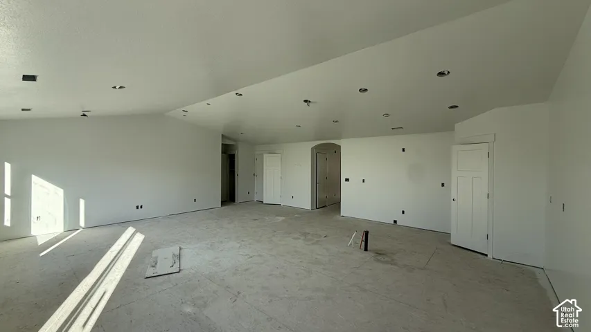 Expansive room with white walls, recessed ceiling lighting, and multiple paneled doors