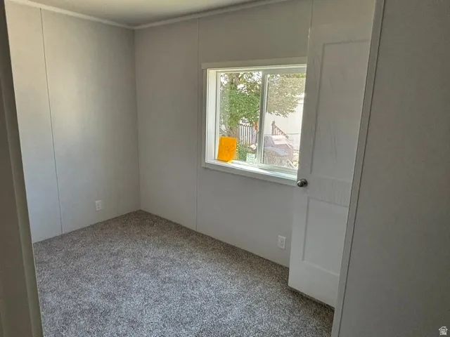 Bedroom featuring light gray paneled walls, gray speckled carpeting, and a white interior door