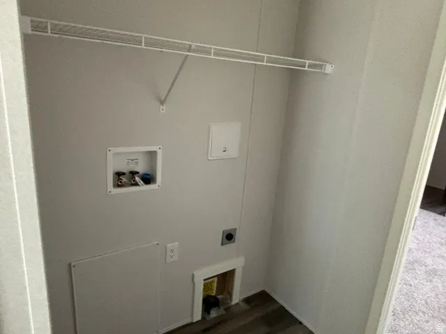 Dedicated utility closet featuring a white wire shelf, hook-ups for laundry appliances, and wood-finish flooring