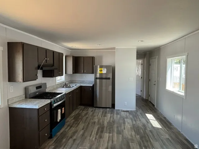 Galley kitchen featuring wood-finish flooring, dark wood cabinetry, and light-toned countertops