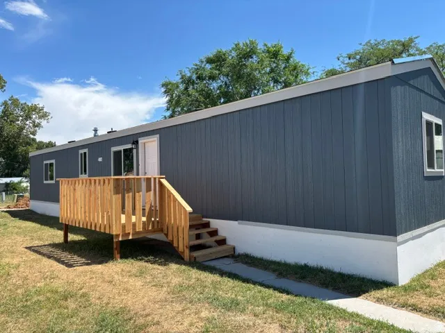 Contemporary exterior with dark gray vertical siding, white trim, a new wood deck, and a white entry door