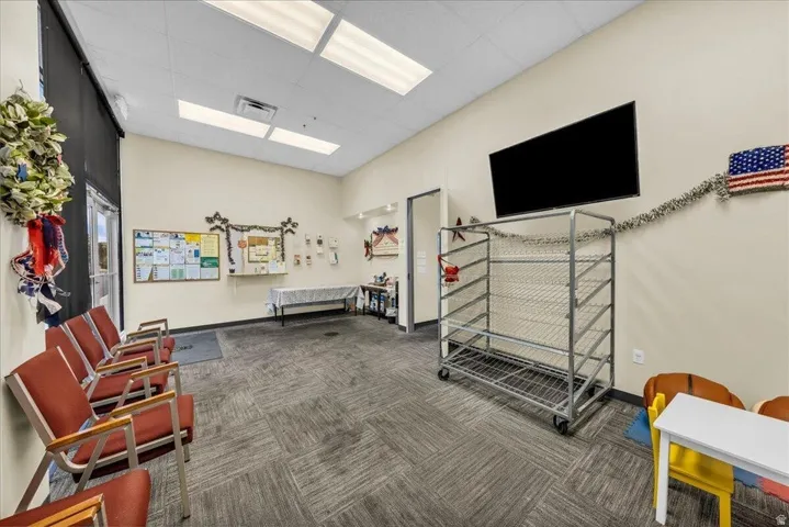 Spacious commercial interior featuring recessed lighting, carpet tile flooring, and a wall-mounted display