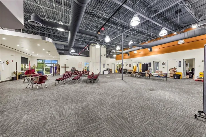 Spacious interior featuring high ceilings, exposed ductwork, recessed lighting, and patterned carpet flooring