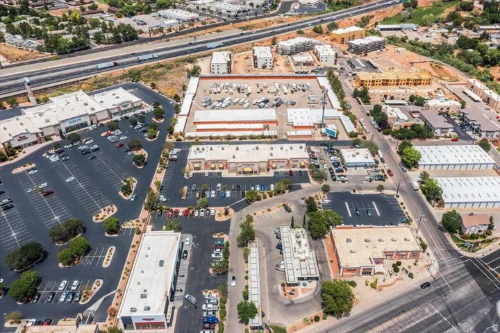 Commercial district with multiple retail and industrial properties, expansive parking areas, and a visible highway infrastructure