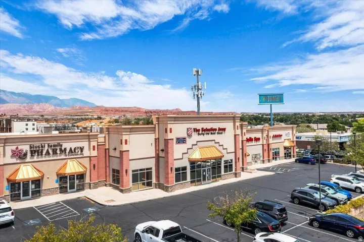 Retail property featuring multiple storefronts with awnings and ample paved parking