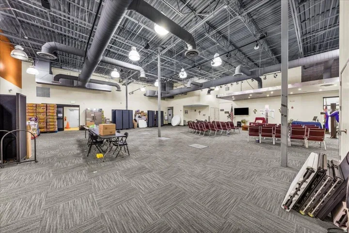 Spacious interior featuring a high exposed ceiling with industrial-style ductwork, recessed lighting, and patterned carpet flooring