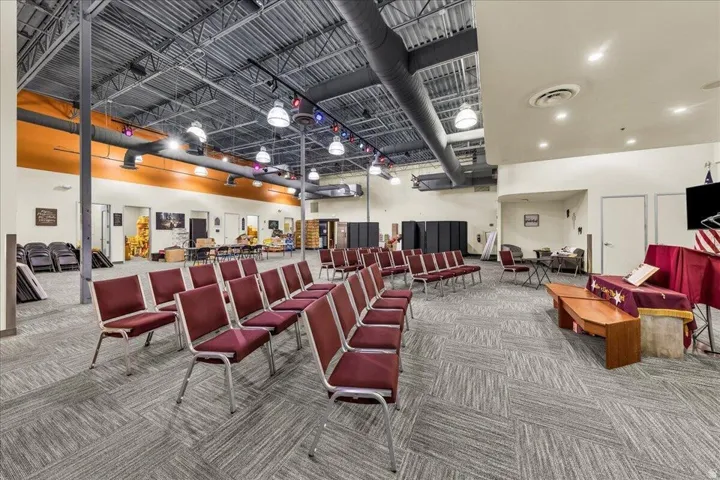 Spacious interior featuring a high exposed ceiling with industrial ductwork and track lighting