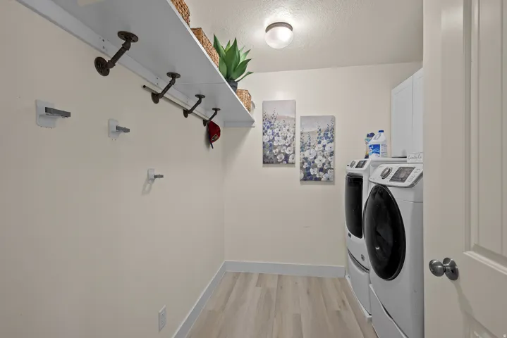 Dedicated laundry area featuring wood-finish flooring and a light-toned color palette