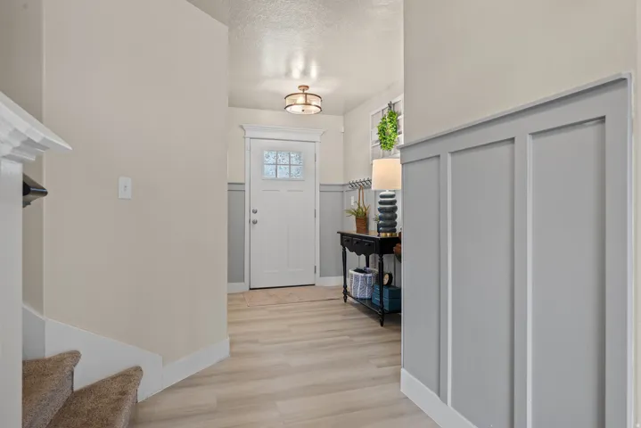Entryway featuring wood-finish flooring, white paneled door with decorative glass, and a decorative semi-flush mount light fixture