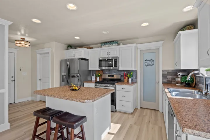 Kitchen featuring white cabinetry, wood-finish flooring, recessed lighting, and a kitchen island with stone-finish countertops