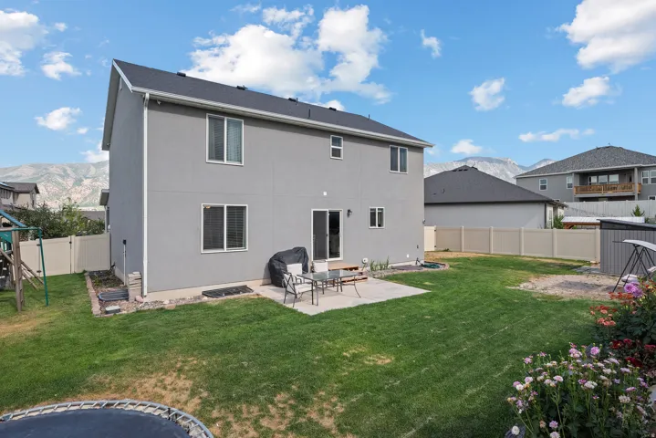 Spacious backyard featuring a concrete patio, expansive lawn, and mountain scenery