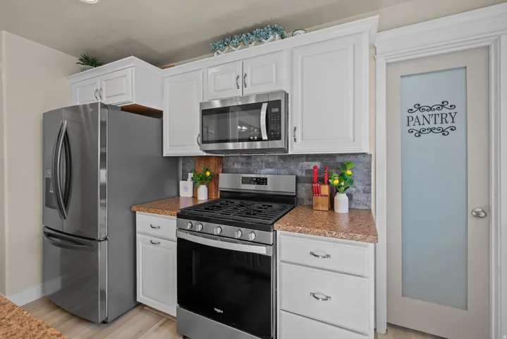 Kitchen featuring white cabinetry, stainless steel appliances, a tile backsplash, and wood-finish flooring