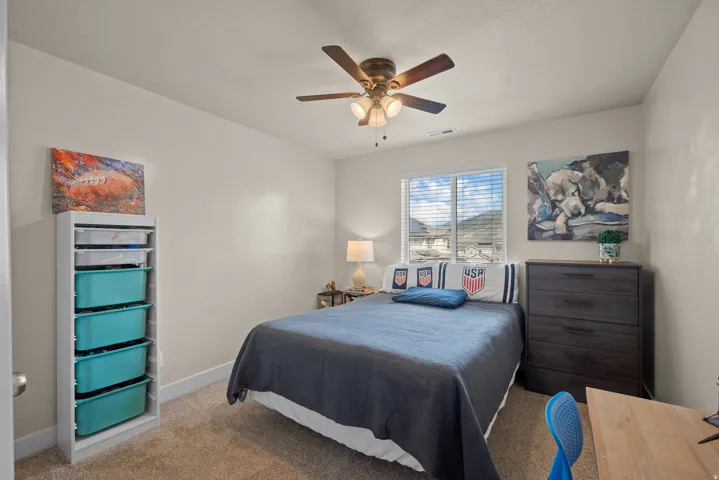 Carpeted room featuring a ceiling fan with integrated lighting, a window with horizontal blinds, and neutral wall tones