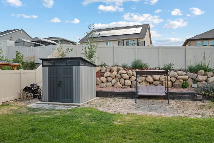 Spacious backyard featuring a storage shed, stone retaining wall, and a full-height privacy fence