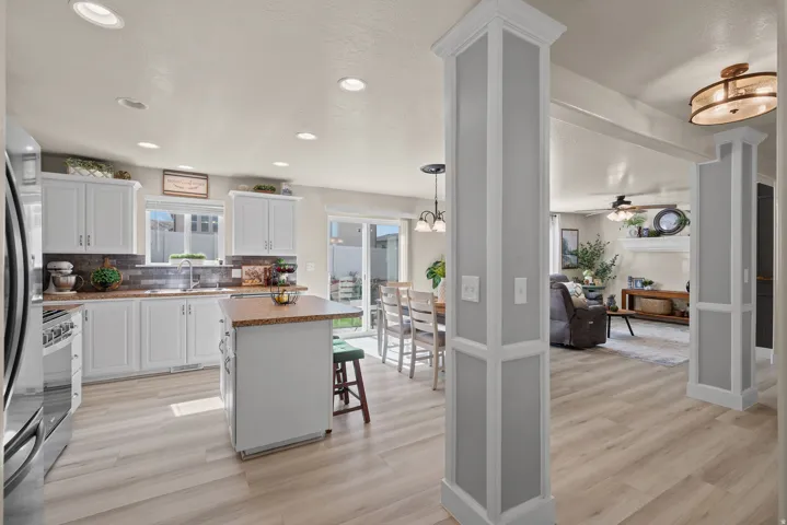 Open-concept kitchen featuring white cabinetry, stone countertops, a subway tile backsplash, and stainless steel appliances